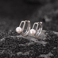 Orecchini ovali minimalisti in argento con perle bianche su sfondo di roccia scura - Stile Perla Ovale Cava / Oro Bianco