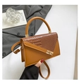 Brown handbag with crocodile texture flap and gold lock displayed on a stylish suit - Brown