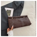 Makroaufnahme der braunen Schlangenhaut-Textur und goldenen Verschlüsse dieser Clutch-Tasche - Braun