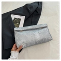 Detail der silbernen Clutch mit Schlangenmuster auf schwarzem Blazer für einen edlen Look - Silber