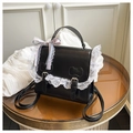 Dettaglio borsa Lolita in ecopelle nera con pizzo bianco e fibbie a fiocco - nero con ciondolo