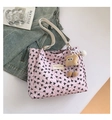 Detail of pink bow-print tote bag with plush charm and chic leather brand label - With Pendant / Pink