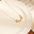 Elegant gold olive branch necklace with emerald gemstones on white porcelain plate - Gold Necklace - Green Zirconia (Olive Leaf Titanium Steel Necklace - Green)
