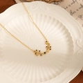 Close-up of golden olive branch pendant with black stones on a white ceramic tray - Gold Necklace - Black Zirconia (Olive Leaf Titanium Steel Necklace - Black)
