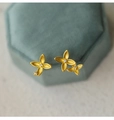 Makroansicht matter goldener Kleeblatt-Ohrstecker mit Diamanten auf grünem Samtkästchen - Asymmetrische Duftblüten Ohrstecker