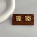 Detailansicht goldene quadratische Ohrstecker mit gewebter Textur auf Holzblock - Gitter-Stil / Gold