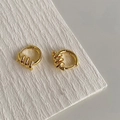 Detailansicht goldener Creolen mit gedrehter Spiralstruktur und Clip-Verschluss - Gold