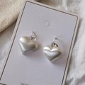 Dettaglio di orecchini a cuore in argento opaco con texture in metallo spazzolato su carta - Clip per Orecchie a Cuore Spazzolato - Argento