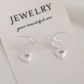 Detail of silver swallow earrings with hammer-textured heart charms and zircon stones - Silver