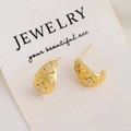 Macro detail of gold C-shaped earrings with star engravings and cubic zirconia stones - C-Shape Stud Earrings / Gold