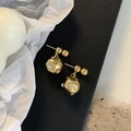 Detail van gouden geometrische bolvormige oorbellen met ingelegde kristallen op een witte basis - Gouden bal oorbellen
