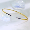 Detalle de brazalete abierto ajustable con filas de circonitas azules en metal dorado - Oro Circonita Azul