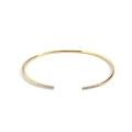 Detalle macro de un brazalete dorado abierto con incrustaciones de circonitas brillantes - Oro Circona Blanca