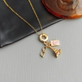 Gold titanium steel necklace with Eiffel Tower, camera and glasses charms on stone surface - Camera Pyramid Necklace-Gold / Gold