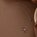 Zilveren badmintonracket ketting met roze emaille shuttle op bruin vintage papier - Roze Zilver