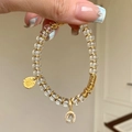 Elegante witte kristallen kralenarmband met gouden Fu-hanger en sprankelend accent - Witte Kristallen Kralen Armband