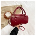 Close-up of wine red PU leather bowling bag with polished gold hardware and top handles - Red