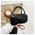 Detail of a black mini bowling bag with gold hardware and an adjustable crossbody strap - Black
