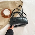 Borsa bowling nera lucida con manici rotondi e tracolla in un contesto casuale - Nero