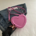 Pink heart-shaped crossbody bag with gold Fashion & Bag text on blue denim background - Barbie Pink