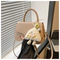 Dettaglio della borsa a sella beige con manico intrecciato e ciondolo a triangolo felpato - Cachi Con Pendente