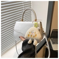 Detailed side view of silver curved flap bag with plush pendant and woven handle - Silver with Charm