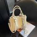 Chic beige lychee textured bucket bag with decorative knot handles and silver charms - 20x16x9cm / Off White