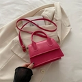 Borsa a tracolla rosa acceso in pelle con manico e cinturino su una giacca avorio - rosa acceso
