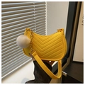 Macro shot of yellow crescent bag featuring V-quilting detail and a white pom-pom - Yellow
