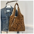Detalle de bolso tote de pana con estampado de leopardo y neceser a juego en una percha - Marrón