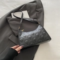 Chic black quilted hobo bag with fish scale texture on a grey suit jacket - Black