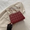 Burgundy quilted chain crossbody bag with gold hardware on beige blazer background - Red