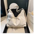 Detalle de bolso hobo crema con textura de cordón y colgante de peluche en una caja - Estilo Con Colgante / Blanco Con Colgante