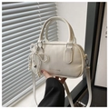 Detailed shot of a white fashion handbag featuring a pearl bow charm and adjustable strap - White