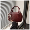 Detail of burgundy glossy Boston bag with pearl bow charm and silver heart pendant - Red
