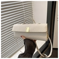 Detailaufnahme der weißen Krokoprägung mit eleganter goldener Metallschnalle an der Handtasche - Weiß