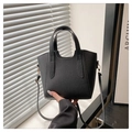 Close-up of black lychee grain texture and metal hardware on a bucket handbag - Black