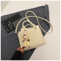 Detail of cream white pebbled leather bucket bag with FASHION logo and pearl charm - Beige With Charm