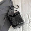 Chic black sequin bucket bag with leather strap on a stylish gray blazer background - Black