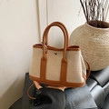 Canvas and brown leather bucket bag featuring a silver metal buckle and crossbody strap - Brown