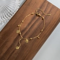 Cavigliera dorata con perline e ciondoli a cuore su legno per un look estivo chic - Oro