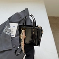 Fashionable black patent leather bucket bag with glossy finish and woven rope charm detail - Charm / Black