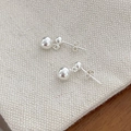 Detailopname van minimalistische dubbele zilveren bolletjes oorbellen op beige linnen - Zilveren ronde bal oorbellen