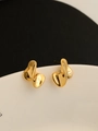 Macro-opname van gouden onregelmatige vloeibare oorbellen met hoogglans op wit keramiek - Goud