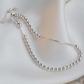 Close-up of silver beaded adjustable bracelet with sliding clasp on white silk fabric - Small Round Bead Bracelet