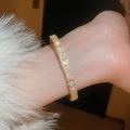 Macro detail of luxury gold bangle with pavé zircons and clover motif on wrist - Gold Eco-Friendly Pave Zirconia Clover Wide Bangle (WZSB329JS)