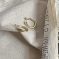Detailopname van matgouden onregelmatig gedraaide oorringen op een beige canvas achtergrond - Matte Ring (Goudkleur)