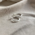 Detailopname van mat zilveren gedraaide oorringen op een getextureerde linnen achtergrond - Matte Ring (Zilver)