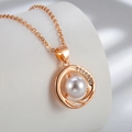 Vista macro di un ciondolo con perla, spirali in oro rosa e dettagli in zirconi lucidi - Oro rosa