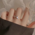 Elegante anello ondulato in argento con pietra di luna indossato sul dito femminile - Stile Abbraccio di Pietra di Luna